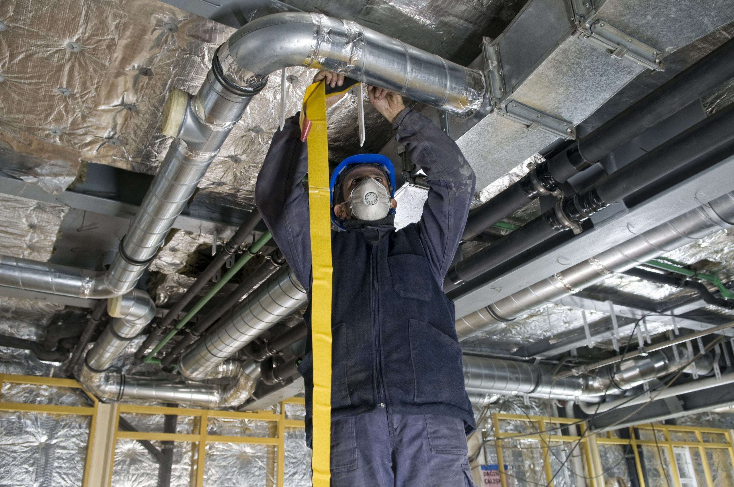 Worker Wrapping An Hvac Air Duct With Foil Tape