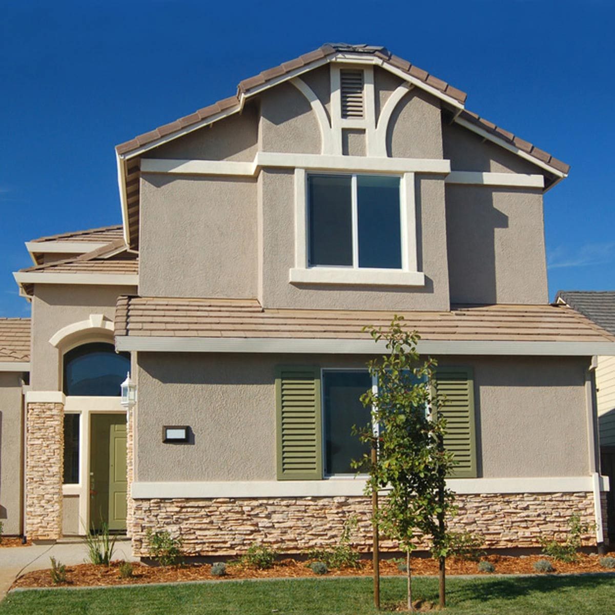 stucco home with white trim and green shutters