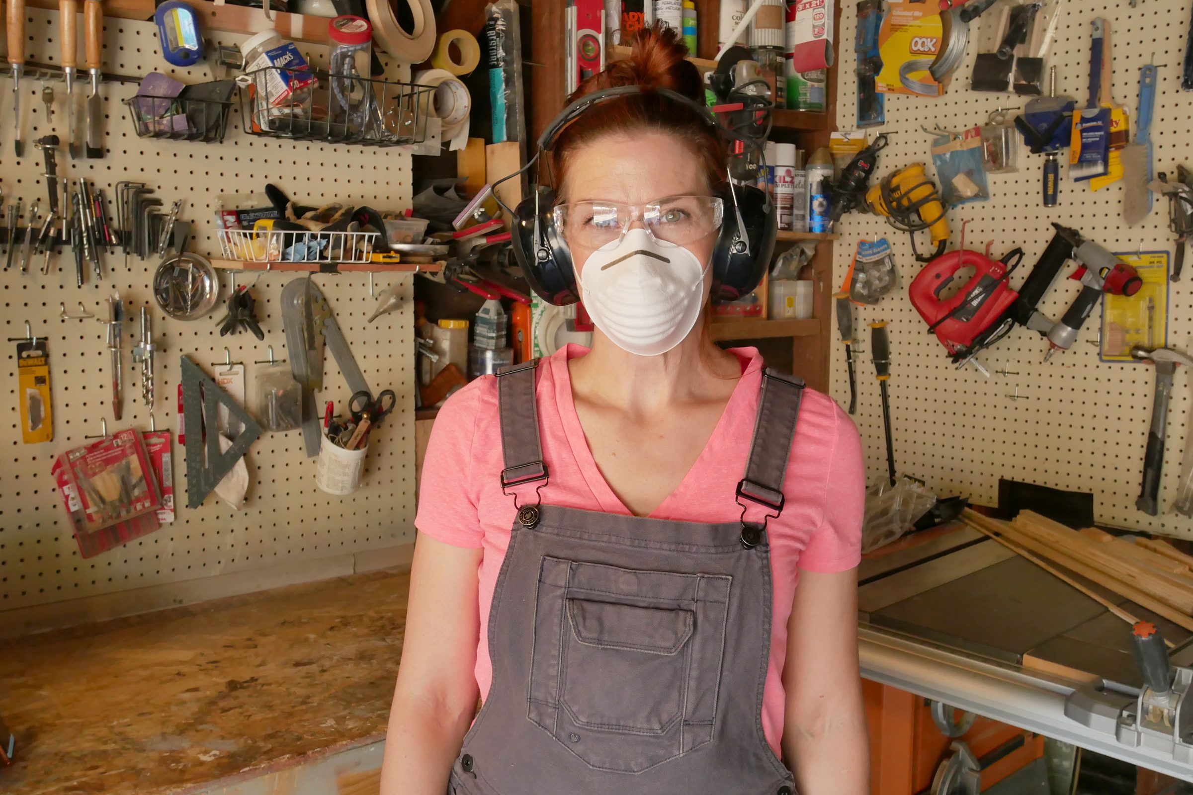 woman with dust mask, ear protection, safety glasses and hair in a bun