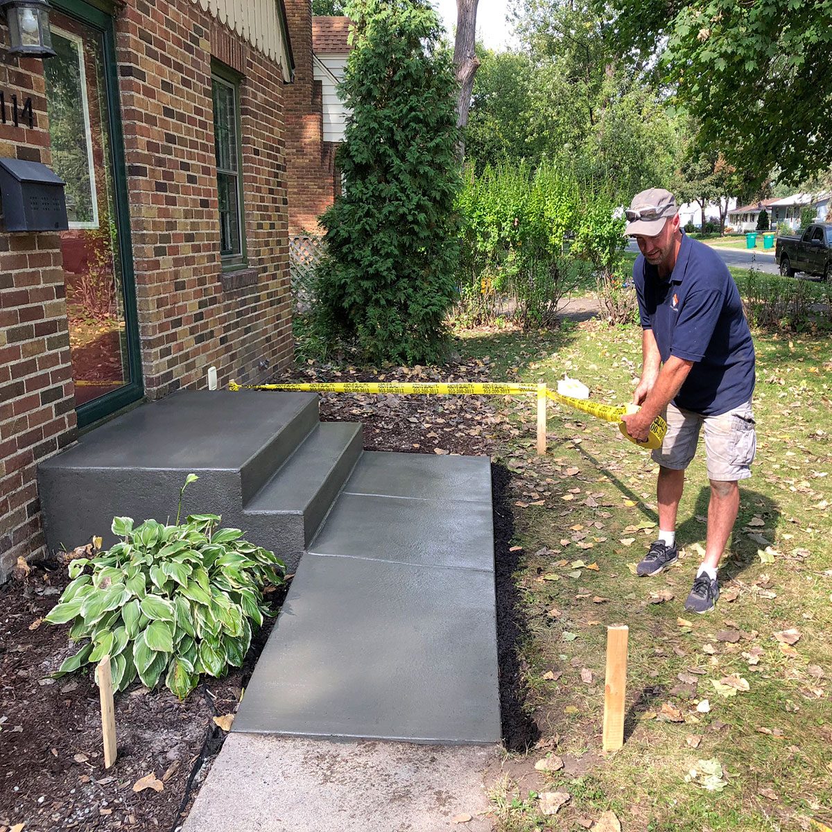 Man placing a tape barricade around a new concrete step | Construction Pro Tips