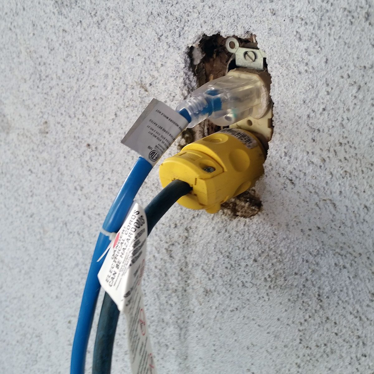 Two cords plugged into a shabby exterior outlet | Construction Pro Tip