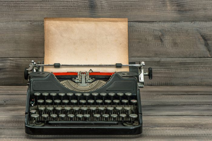 antique typewriter with grungy textured paper page on wooden table. vintage style still life