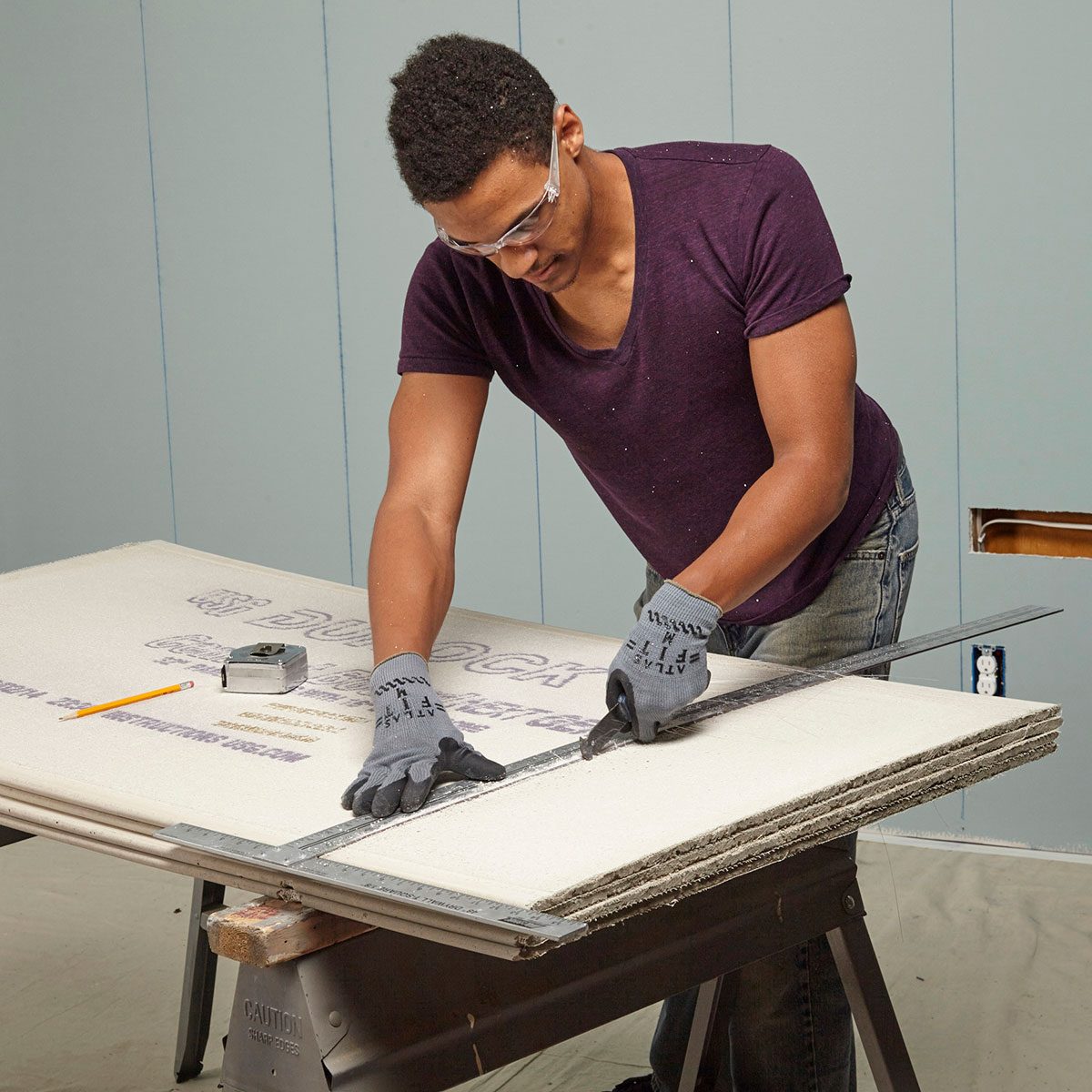 Man scoring a straight line into cement board