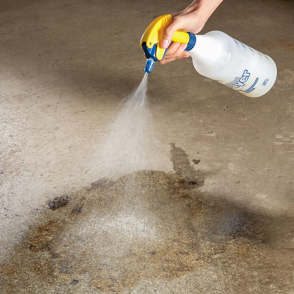 Spraying Oil & Grease Cleaner onto the oil stain