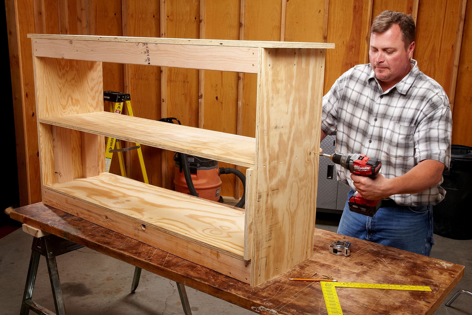 A Man Fastens Screw into Wood with Drill