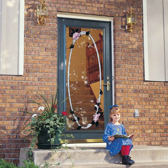 little girl sits with a book on concrete steps in front of a new exterior door