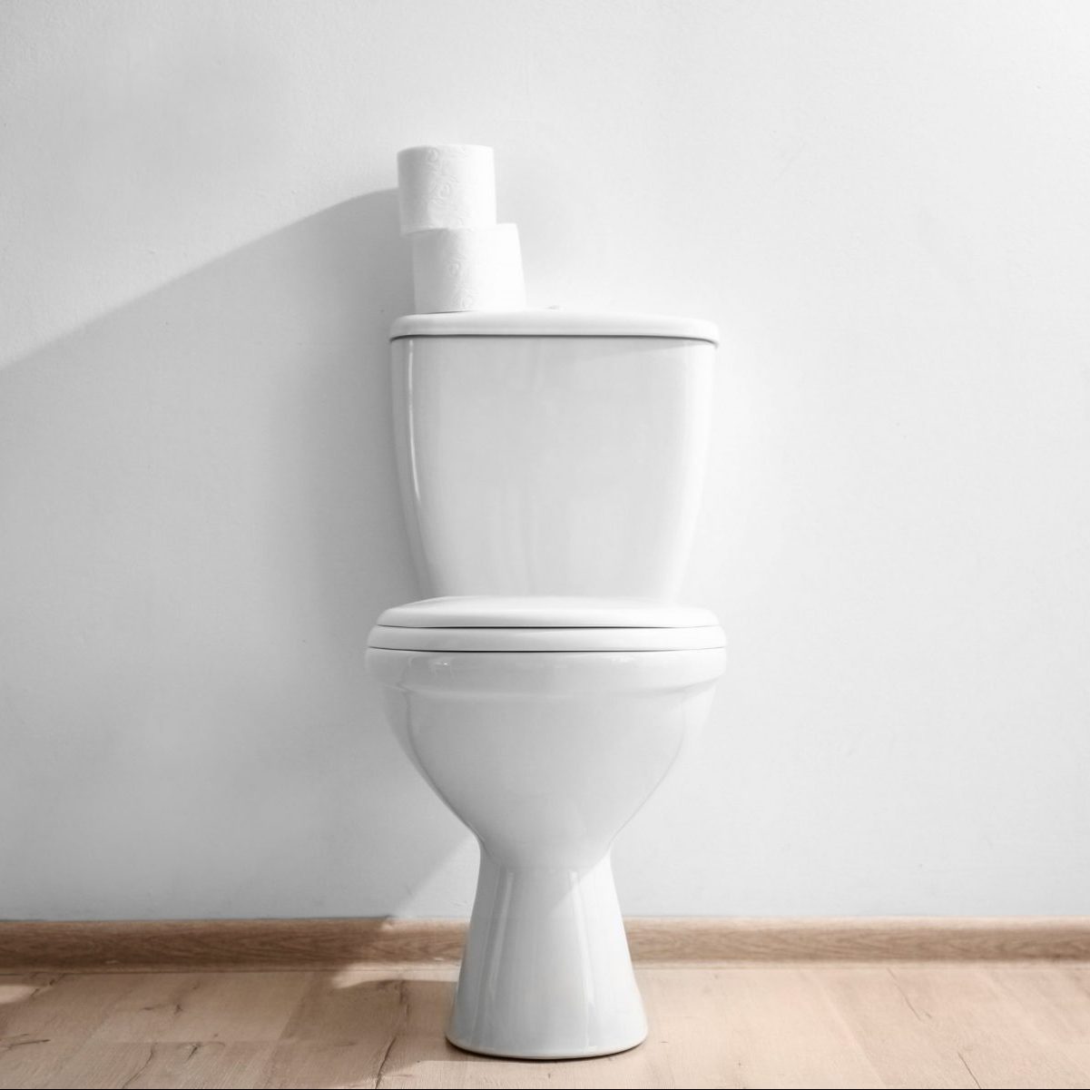 New ceramic toilet bowl near light wall