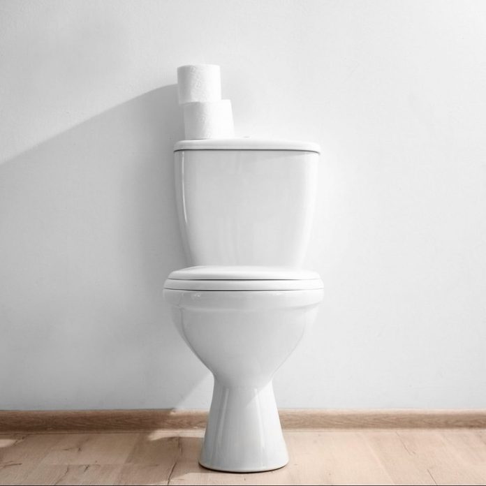 New ceramic toilet bowl near light wall