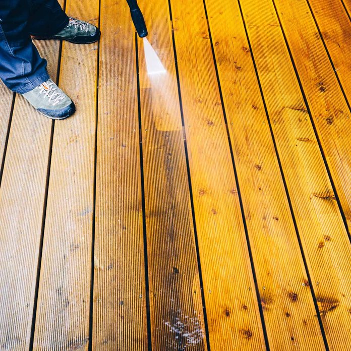 Man-pressure-washes-a-deck