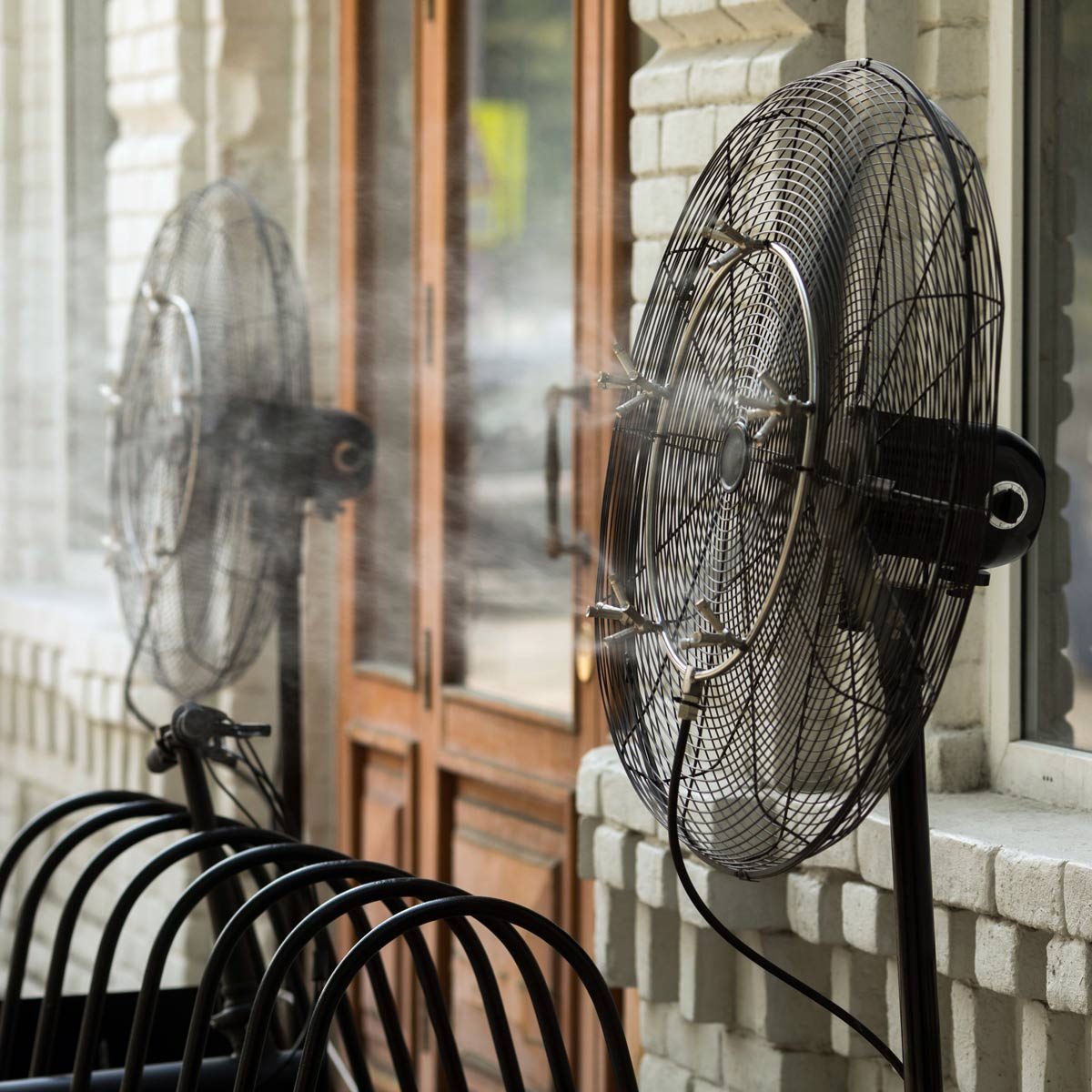 Contemporary system of fans with pulverizes spraying water with air and cooling air outdoors in hot summertime