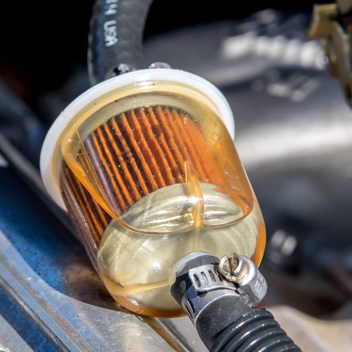 A fuel filter in a car. Gasoline can be seen in the filter. Closeup view.