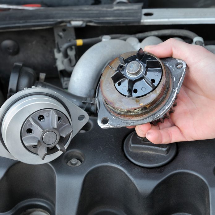 Car mechanic replacing water pump of modern engine