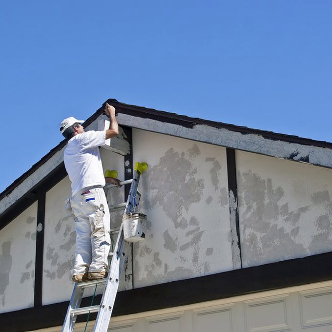 Painter on a ladder uses brown paint