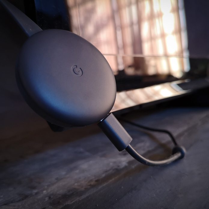 Google HD Chromecast 3rd generation connected to a big black screen television in living room in a house.