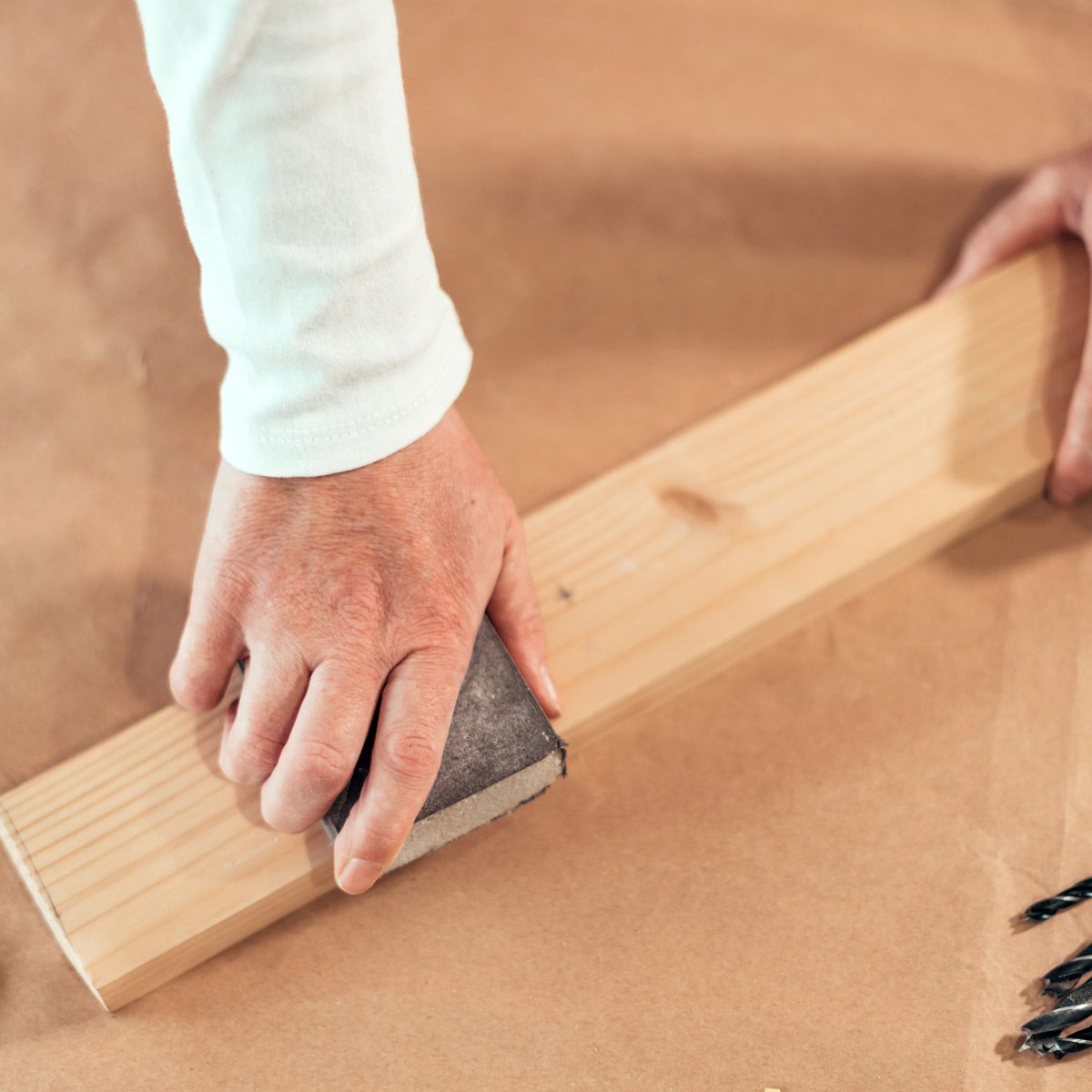 sanding wood plank with sanding sponge