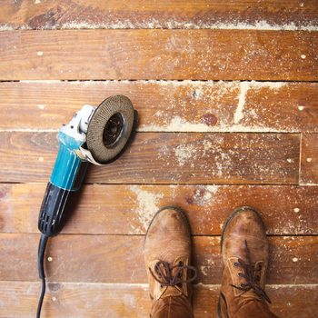 Electric grinder machine left on dusty wooden flooring with wood shavings