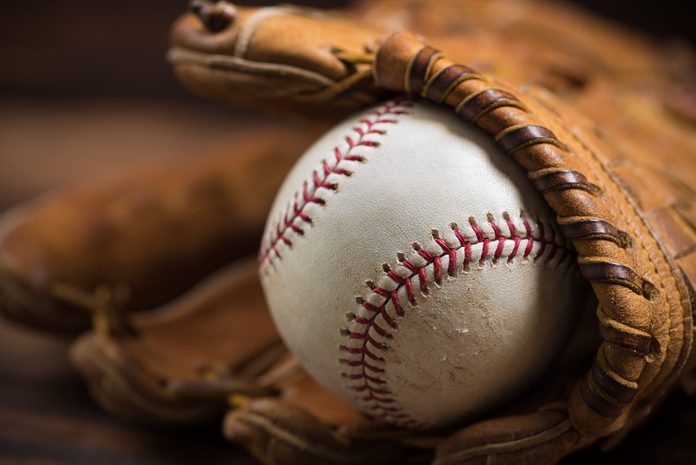 Brown leather baseball glove on a wooden bench