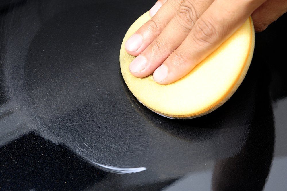 Hand applying polish on black car