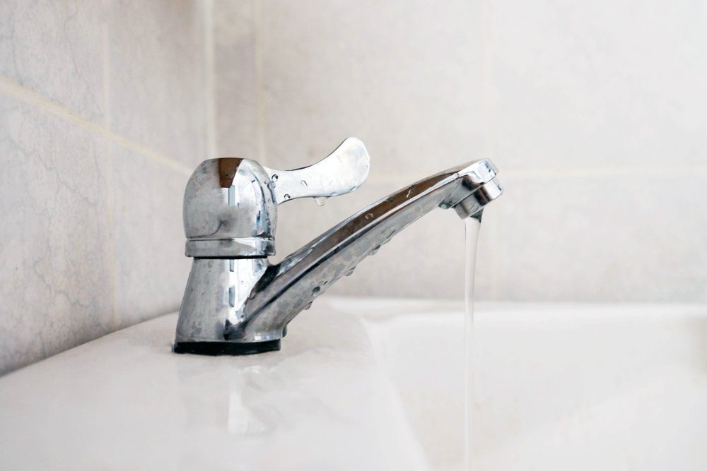 Close up dripping water drop of faucet in the bathroom , save water concept