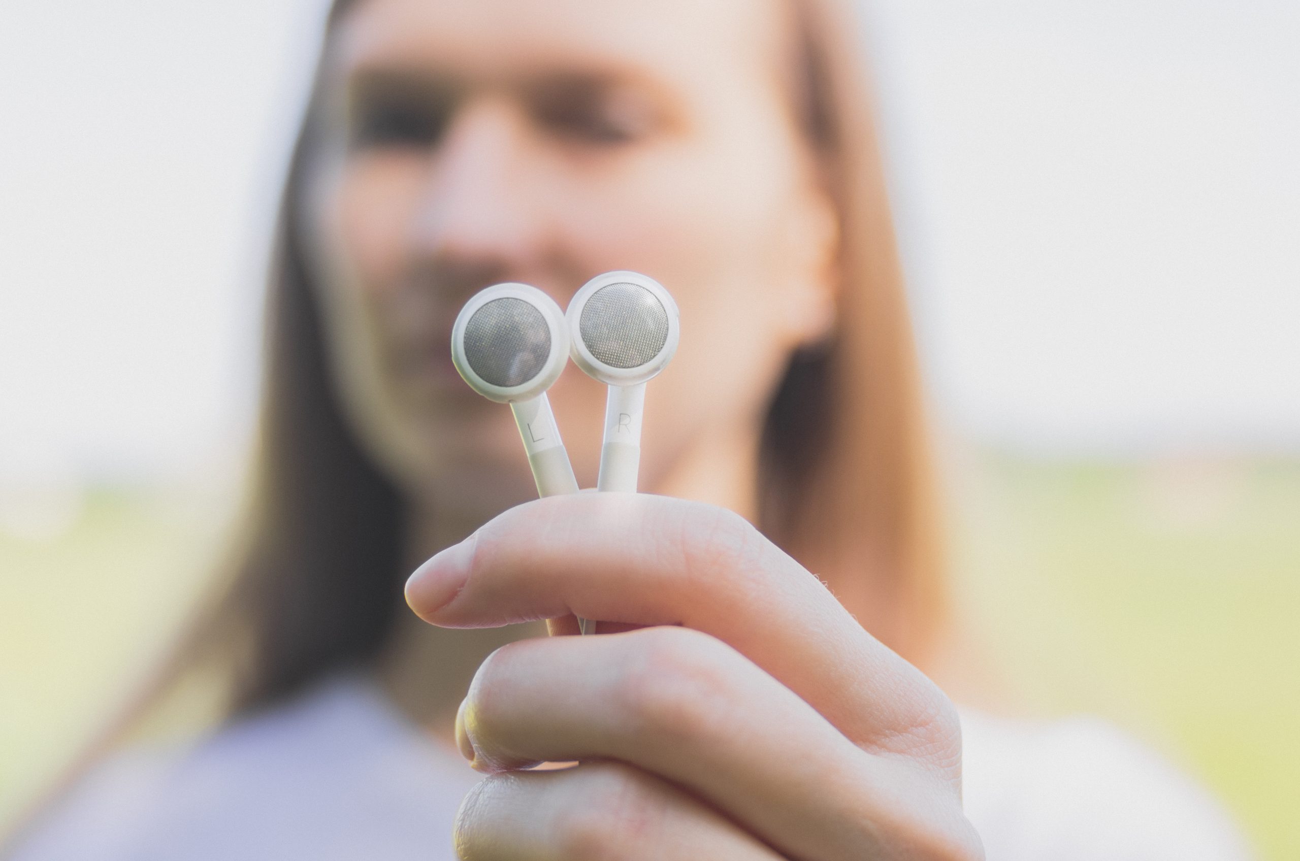 Young woman holds in her hands white earbud headphones