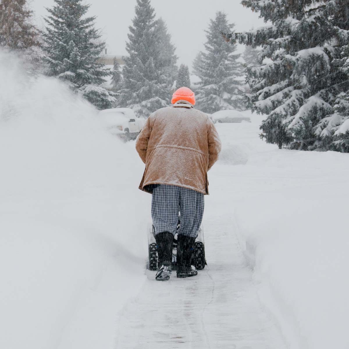 Man pushing snow blower in storm