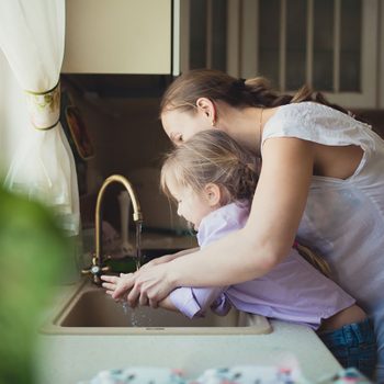 Daughter with her mother to wash their hands in the kitchen sink
