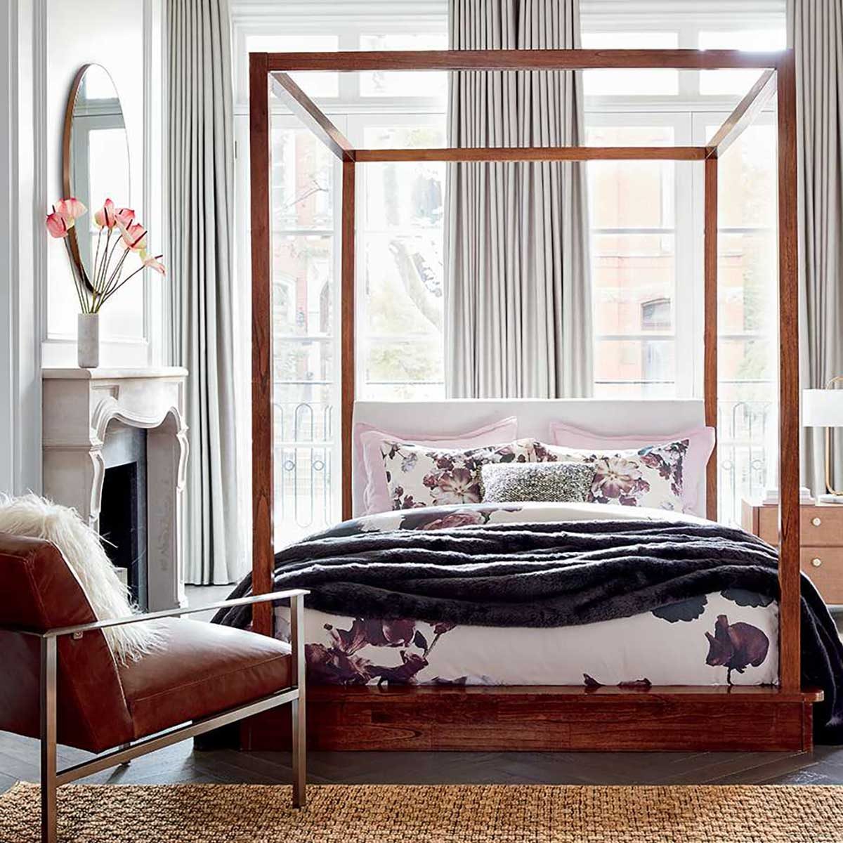 Bedroom with four poster bed and floral blanket.