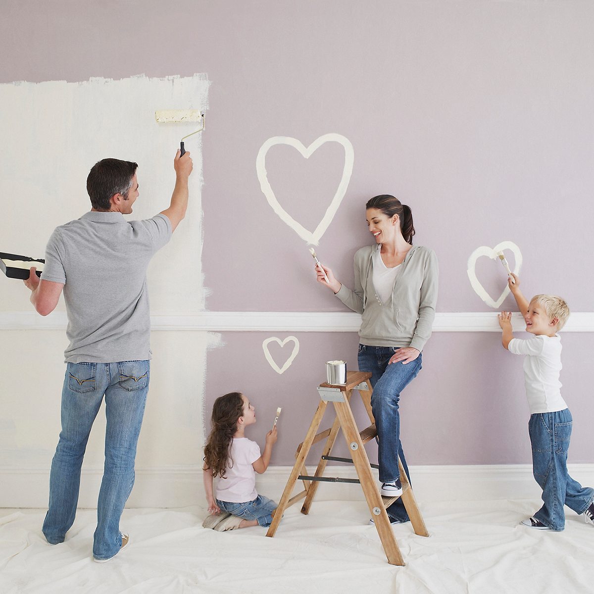 Man and woman with boy and girl painting hearts on wall