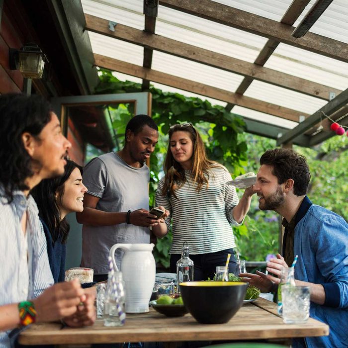 People gathering under a pergola with a plastic cover
