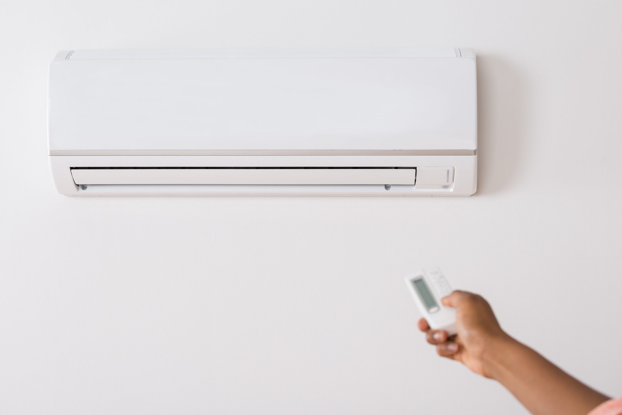 Person's Hand Holding Remote To Operate Air Conditioner