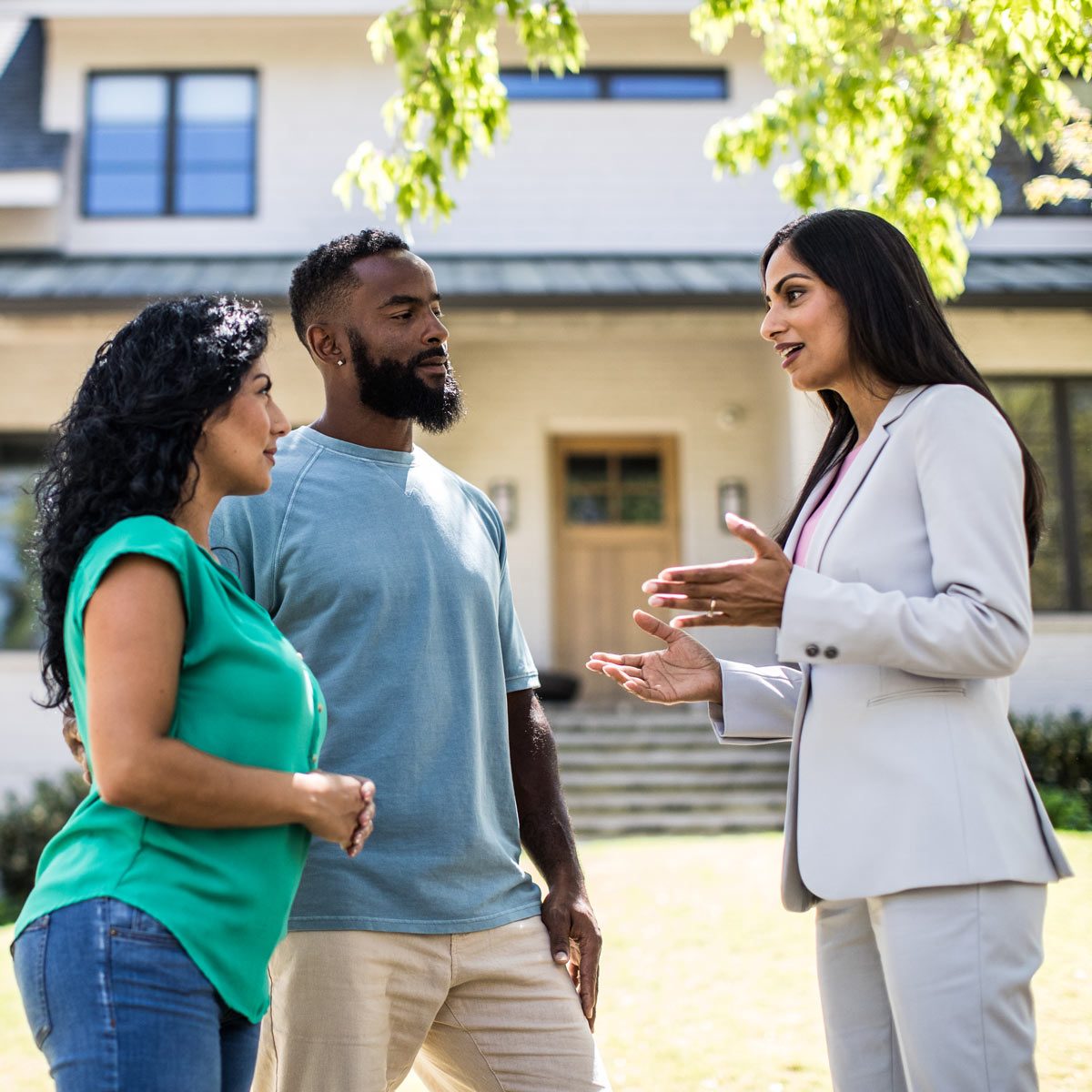 Couple meeting with real estate agent in front of home