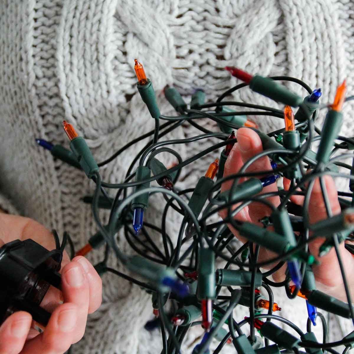 hands holding broken Christmas lights