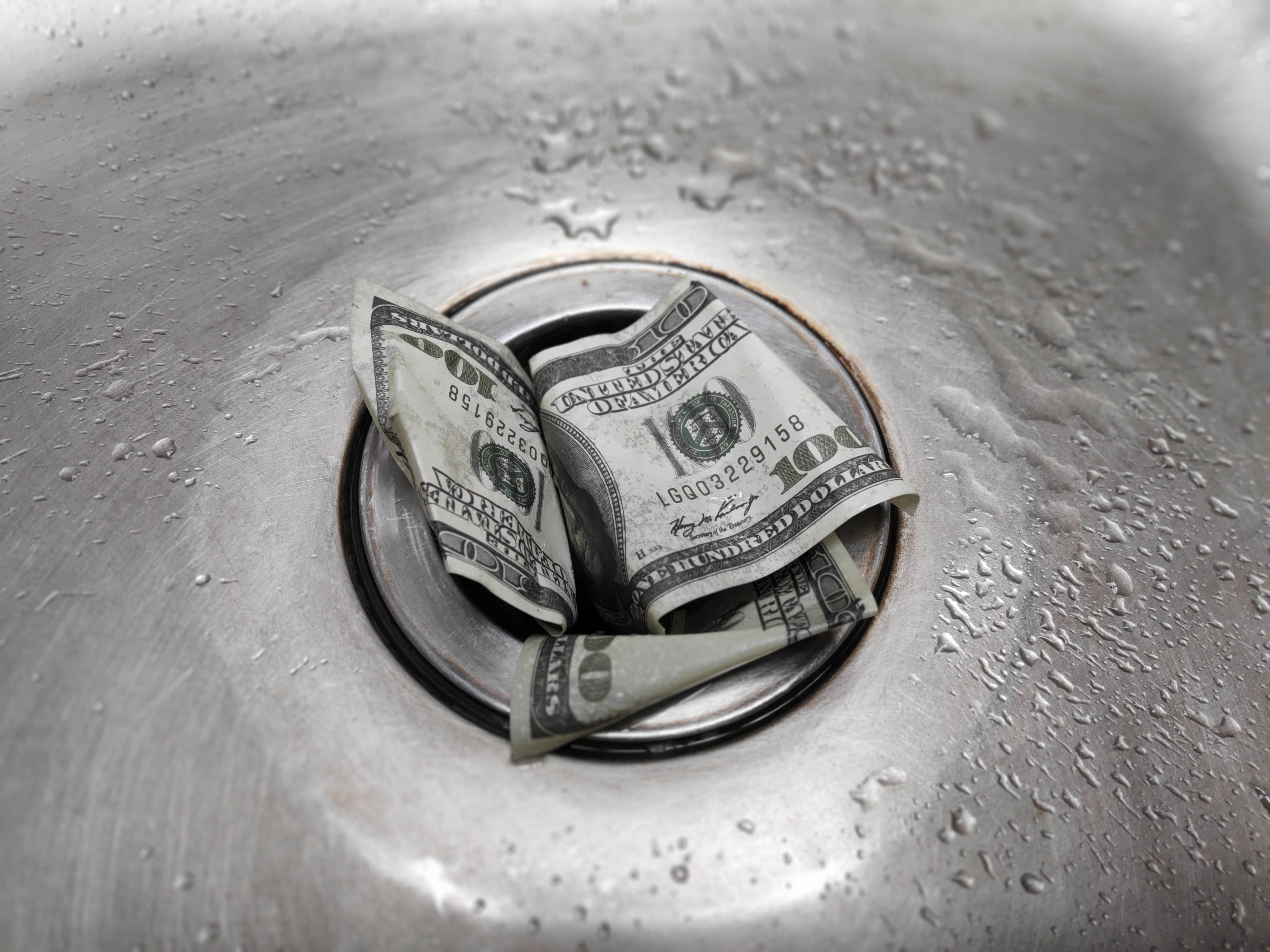 Money is thrown away in the sink. This photo concept illustrates the financial condition of a business that is failing or going bankrupt so that it only wastes money without results.