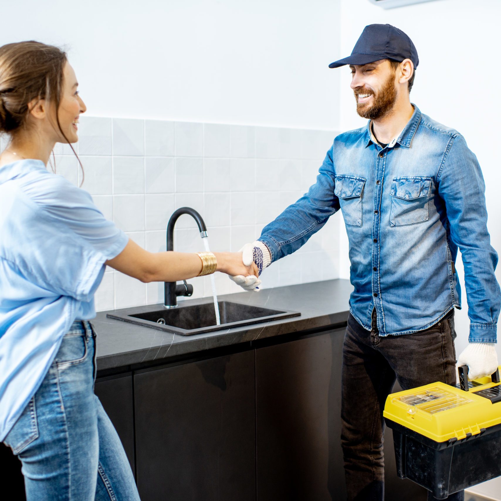 Handy man having a deal with young woman client after the repairment on the kitchen. Home repair service concept