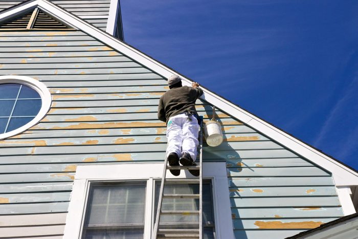 Low Angle View Of Man Painting House While Standing On Ladder