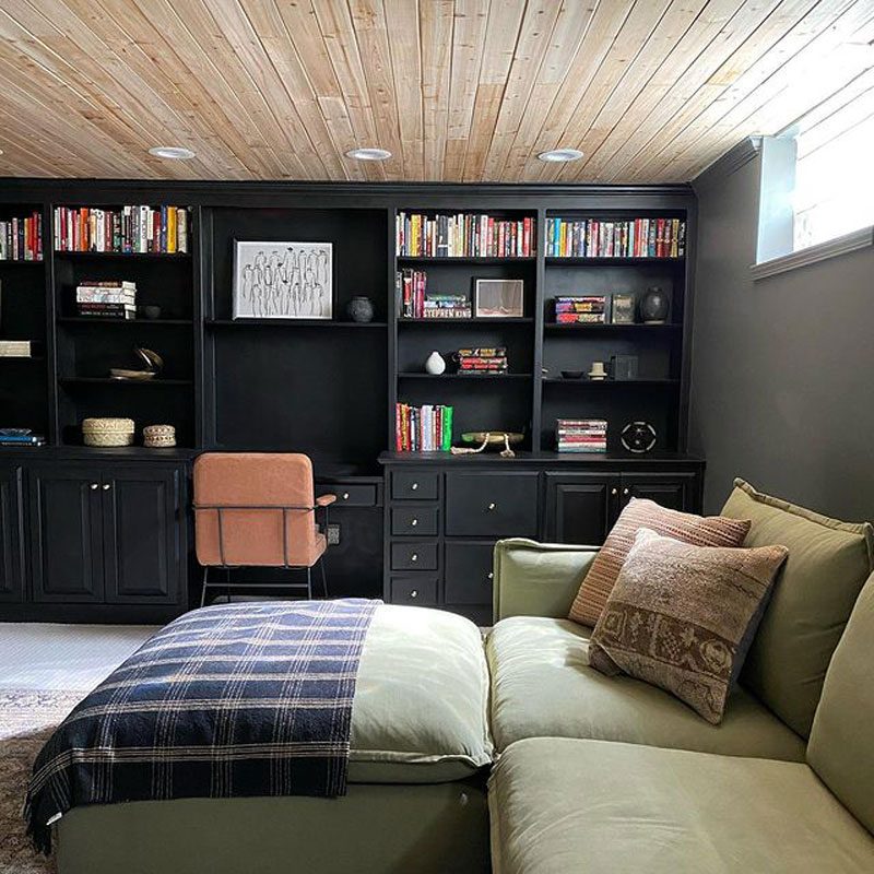 A built-in black shelf in a bedroom with a green bed and couch