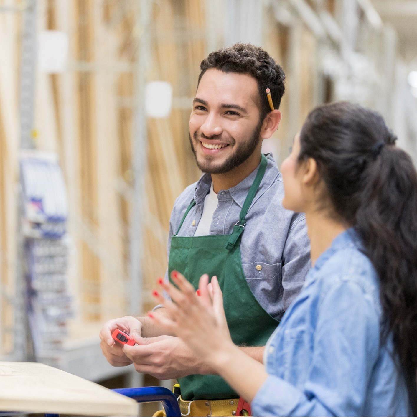 Cheerful lumber yard employee assists female customer