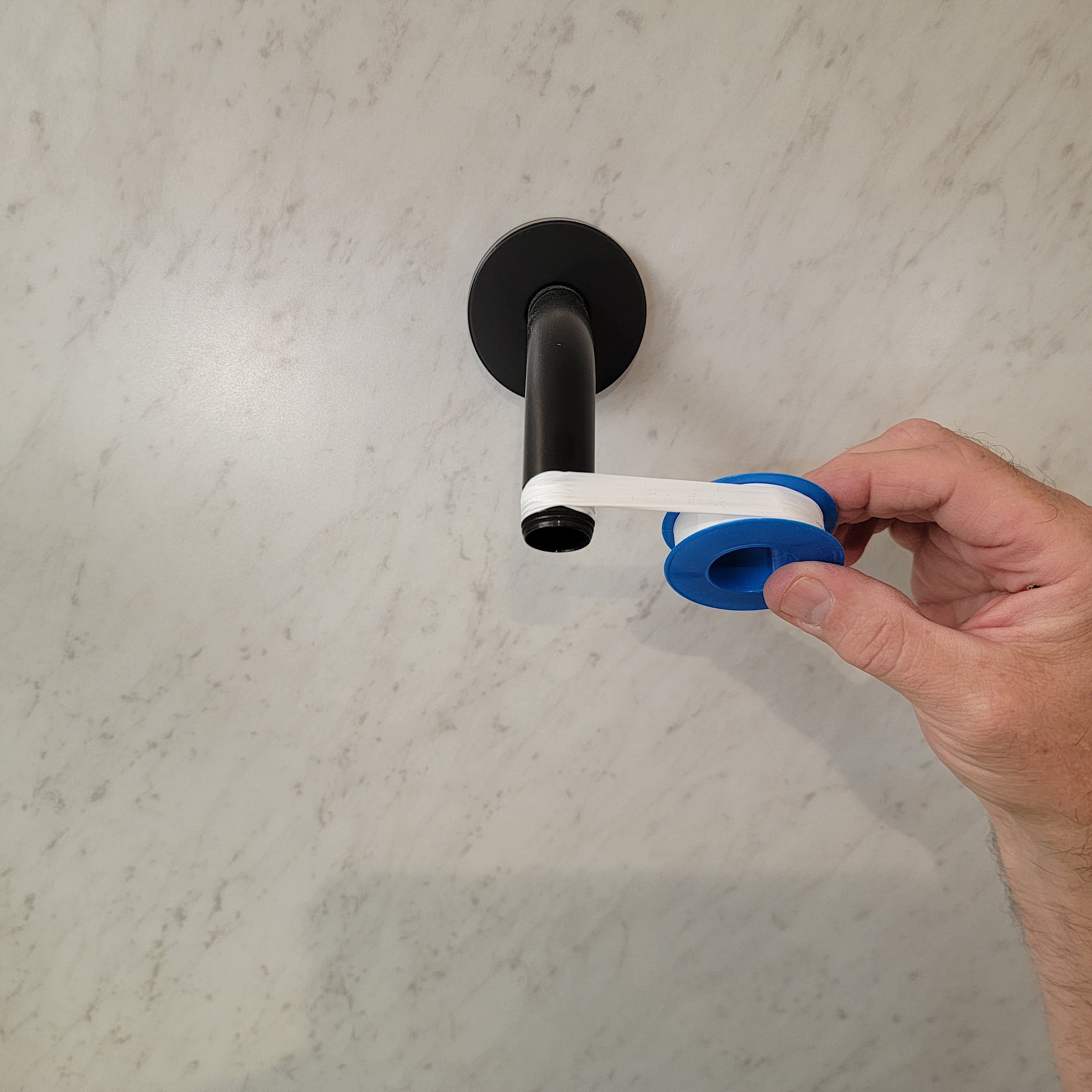 applying plumbers tape to shower head