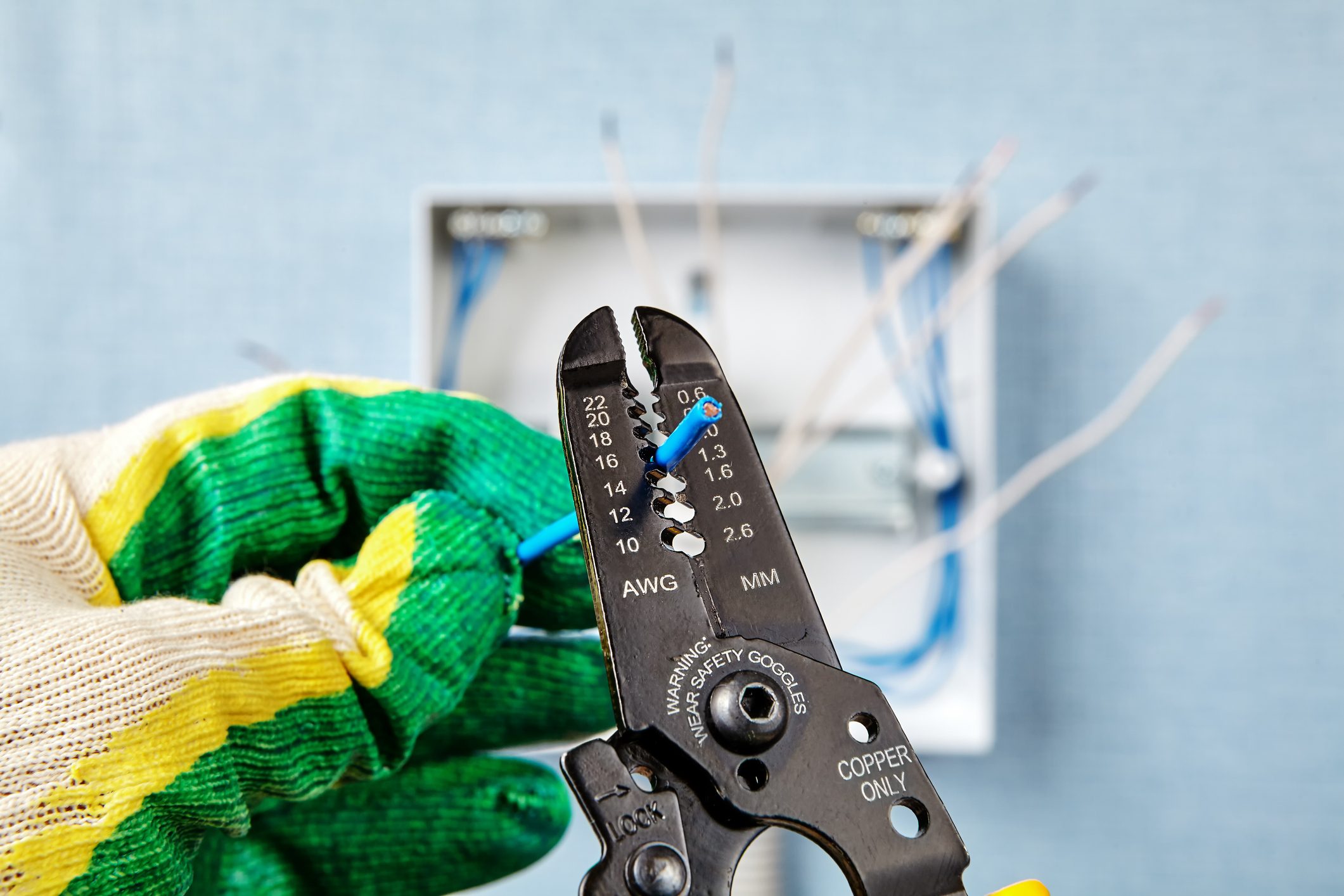 electrician using wire strippers on electrical wire