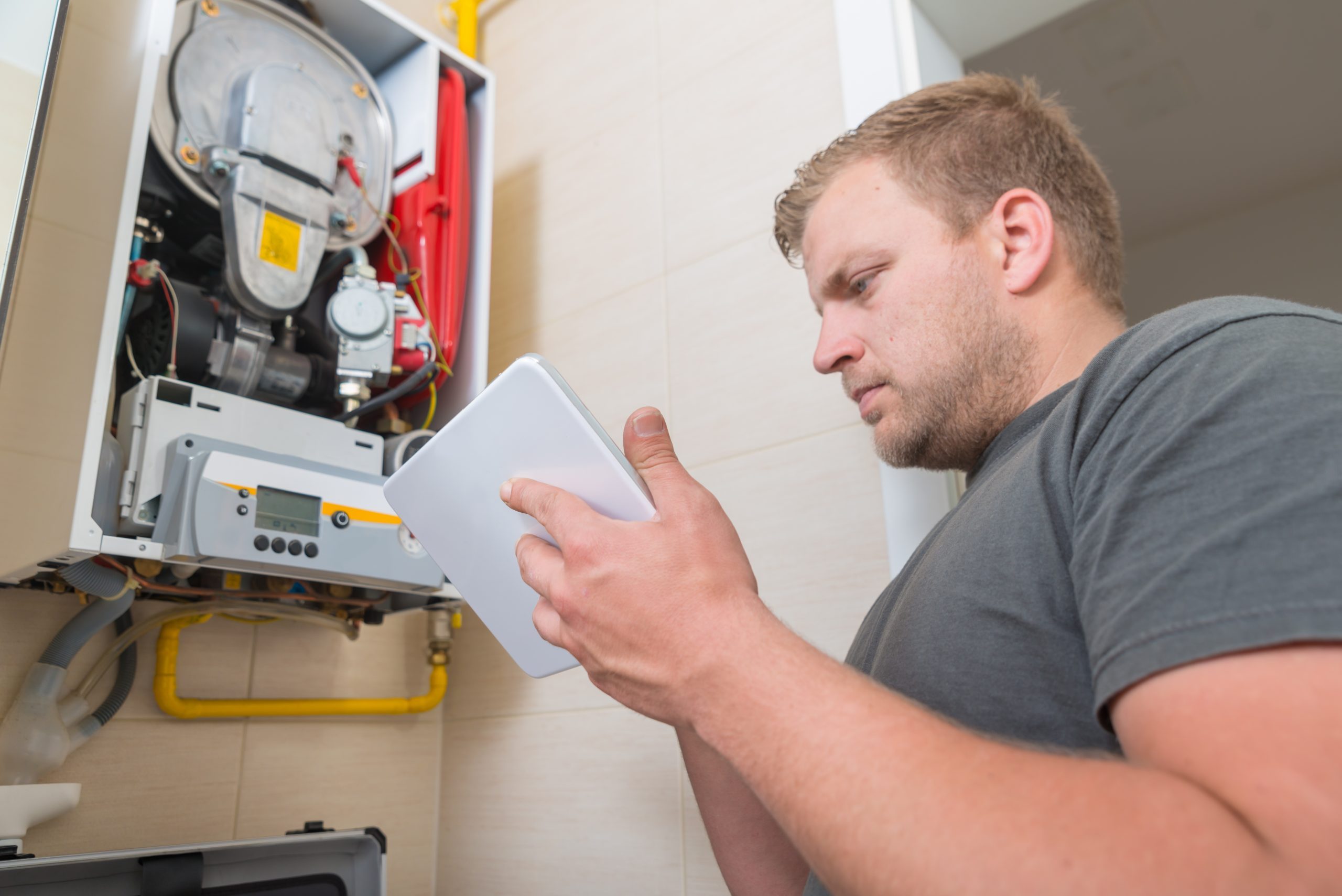 Technician Repairing Gas Furnace Using Digital Tablet