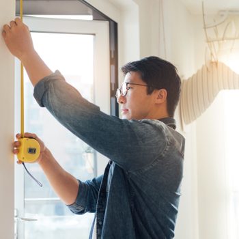 Young Man Doing DIY Using Measuring Tape At Home