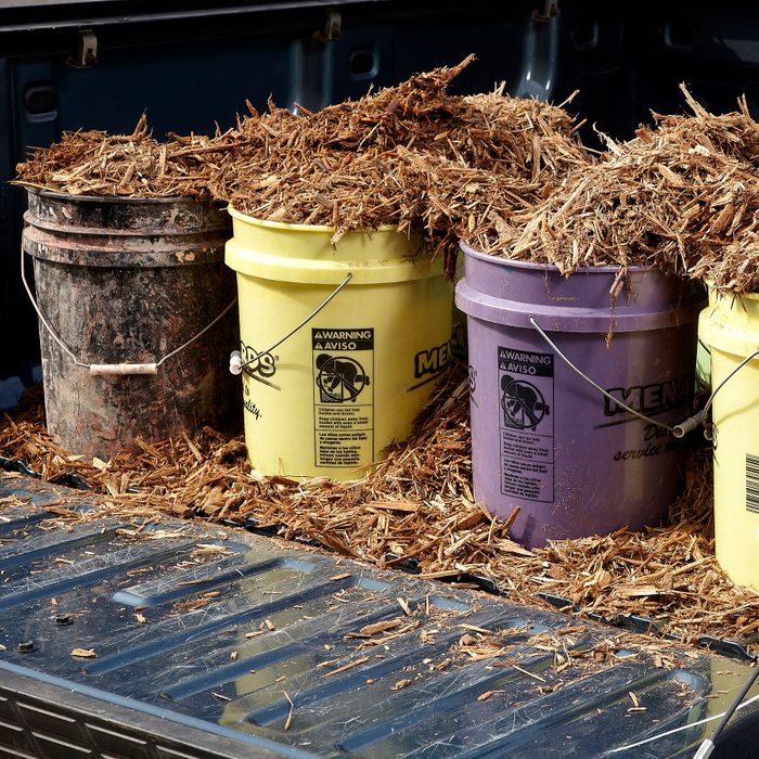 many 5 gallon buckets in the back of a pickup truck with the tail gate open; mulch in the buckets in the truck bed