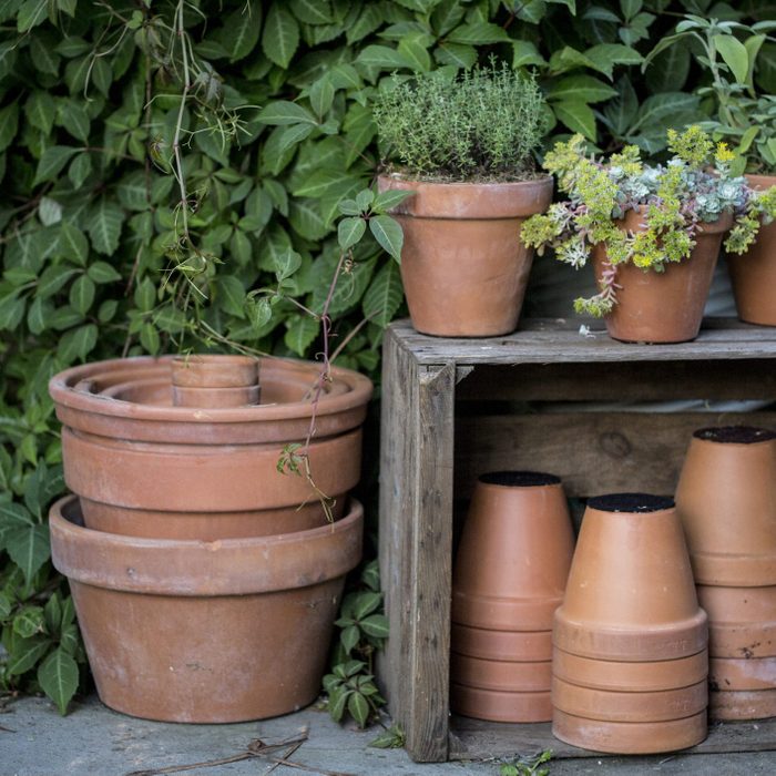 Close up of stacks of terracotta flower pots on a stone floor and wooden box.