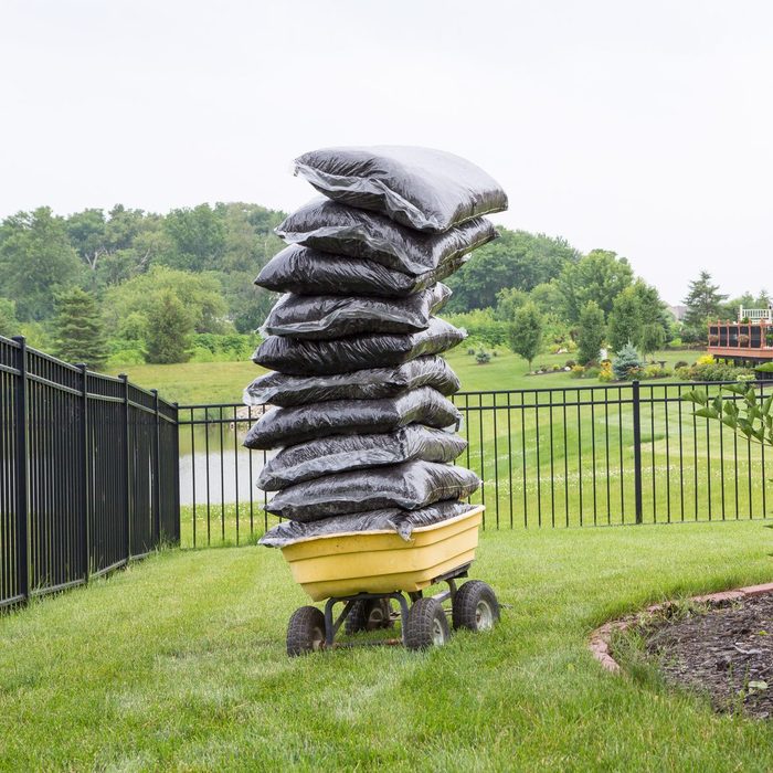 Mulch bags piled high on a cart in the garden