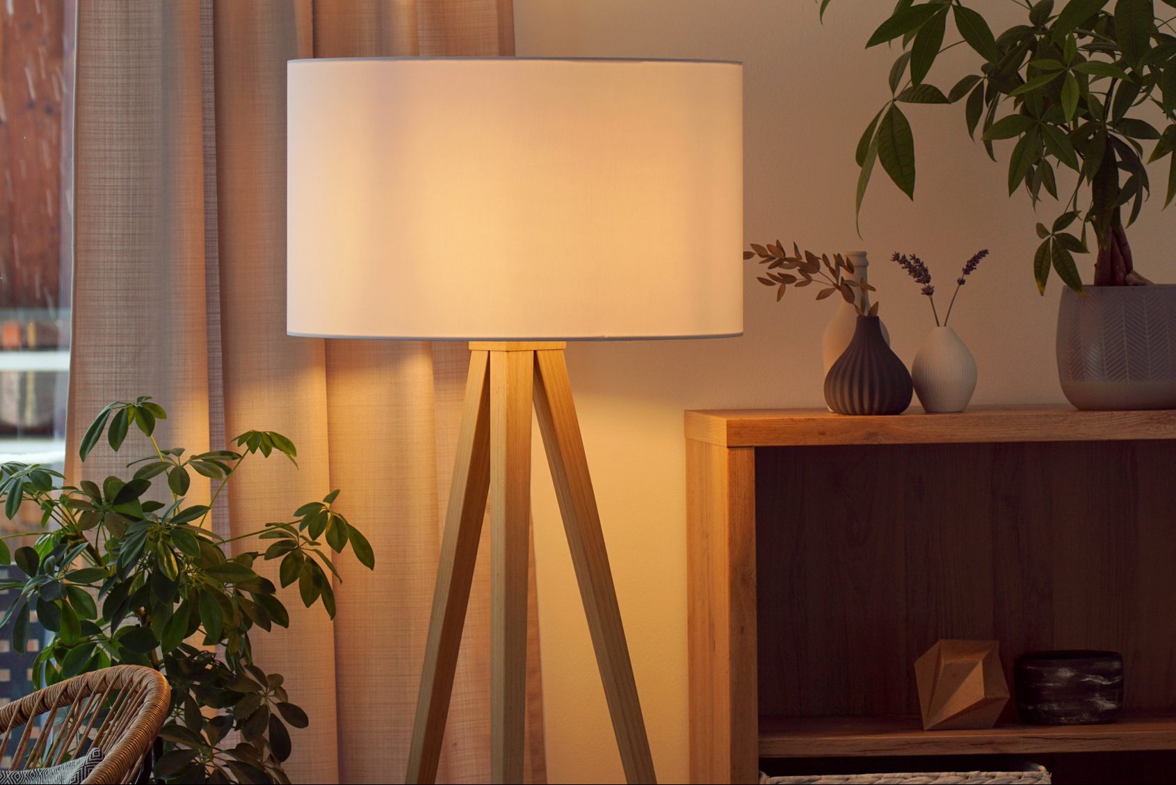 View of tripod lamp in a cozy living room spending warm light