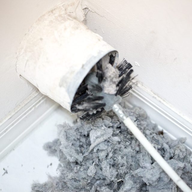 Lint being removed with a brush from a dryer vent