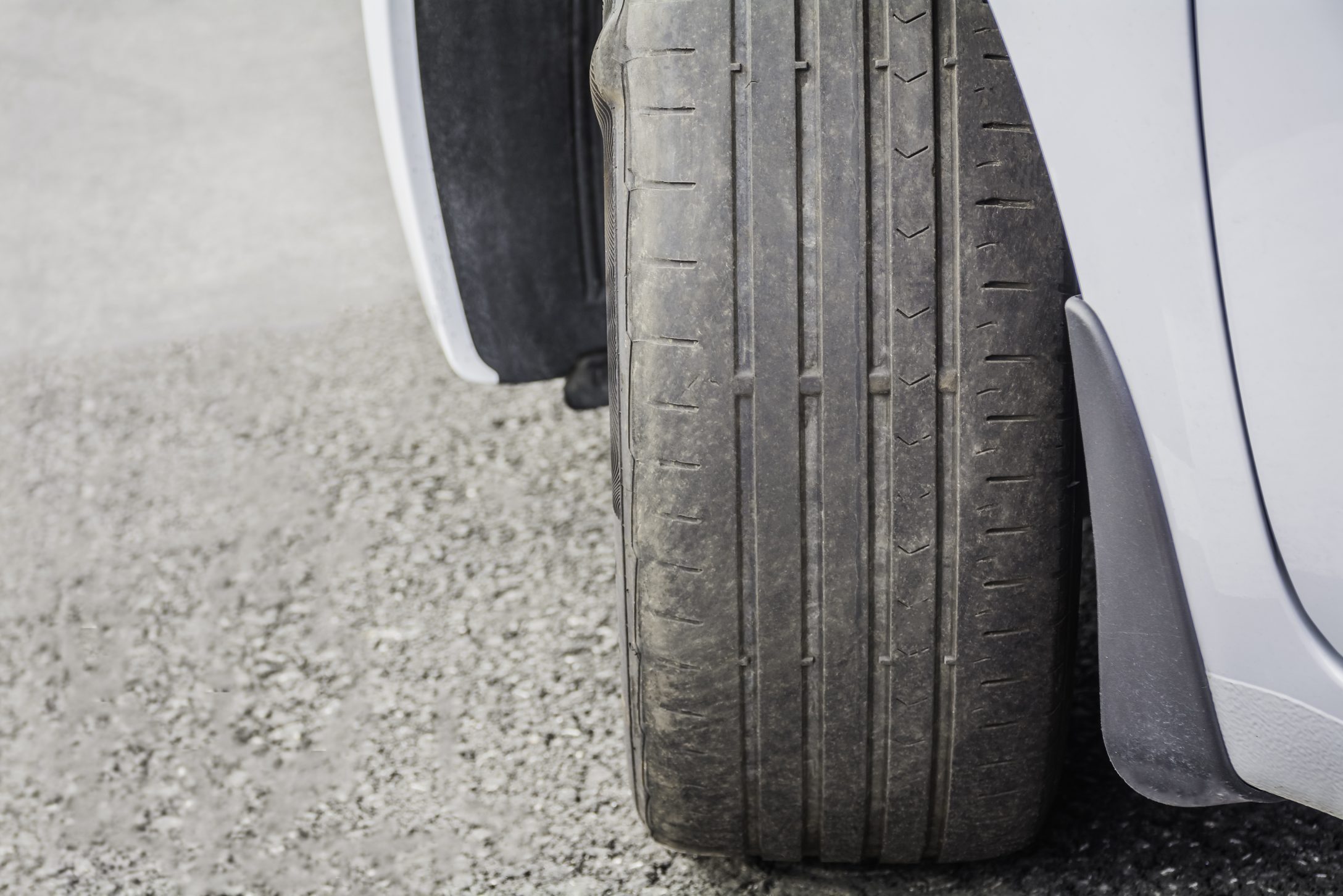 Badly worn out car tire tread due to wear and tear or because of poor tracking or alignment of the wheels