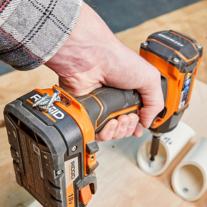 man holding a drill with magnets on the back to hold screws as he is working