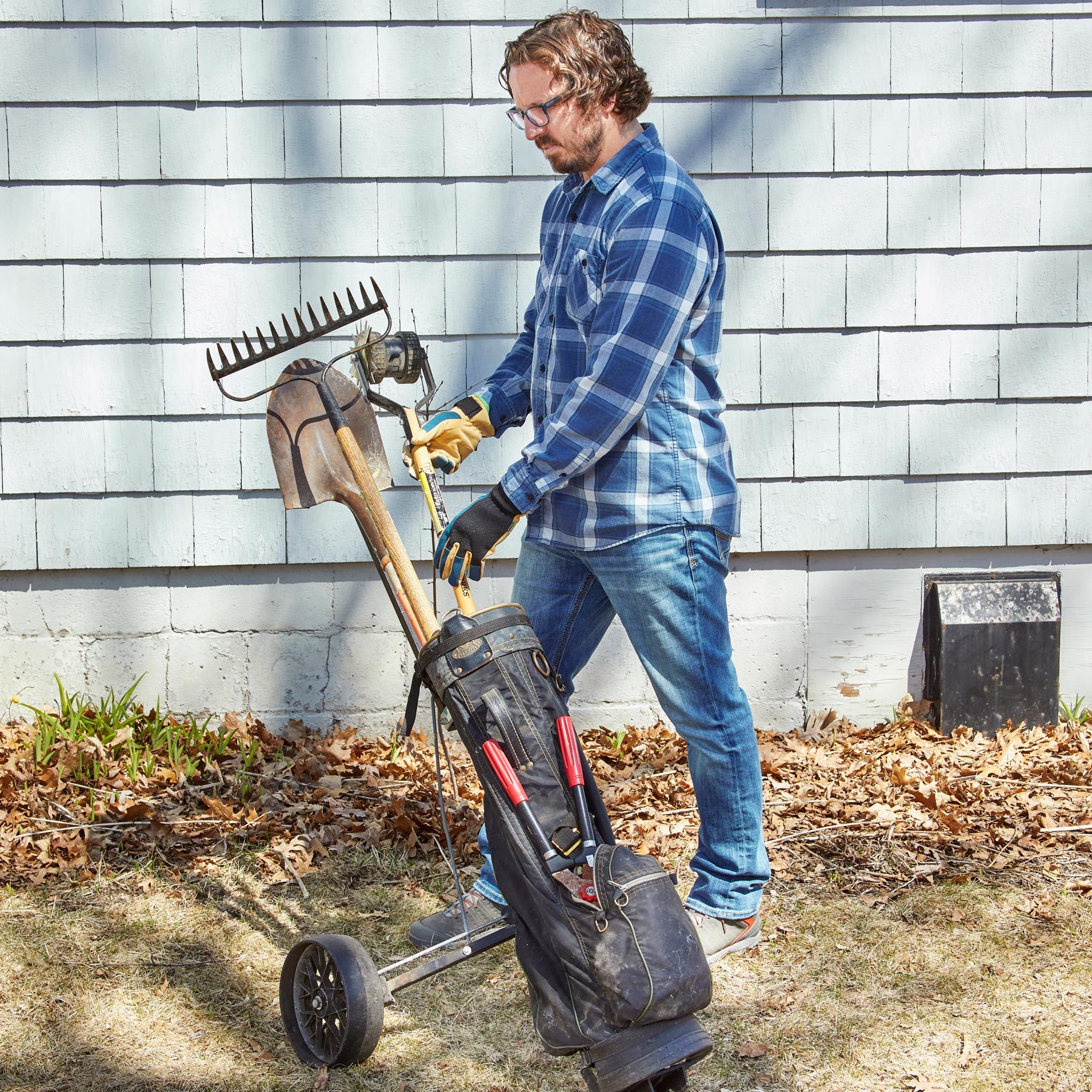 man with golf caddy holding yard tools