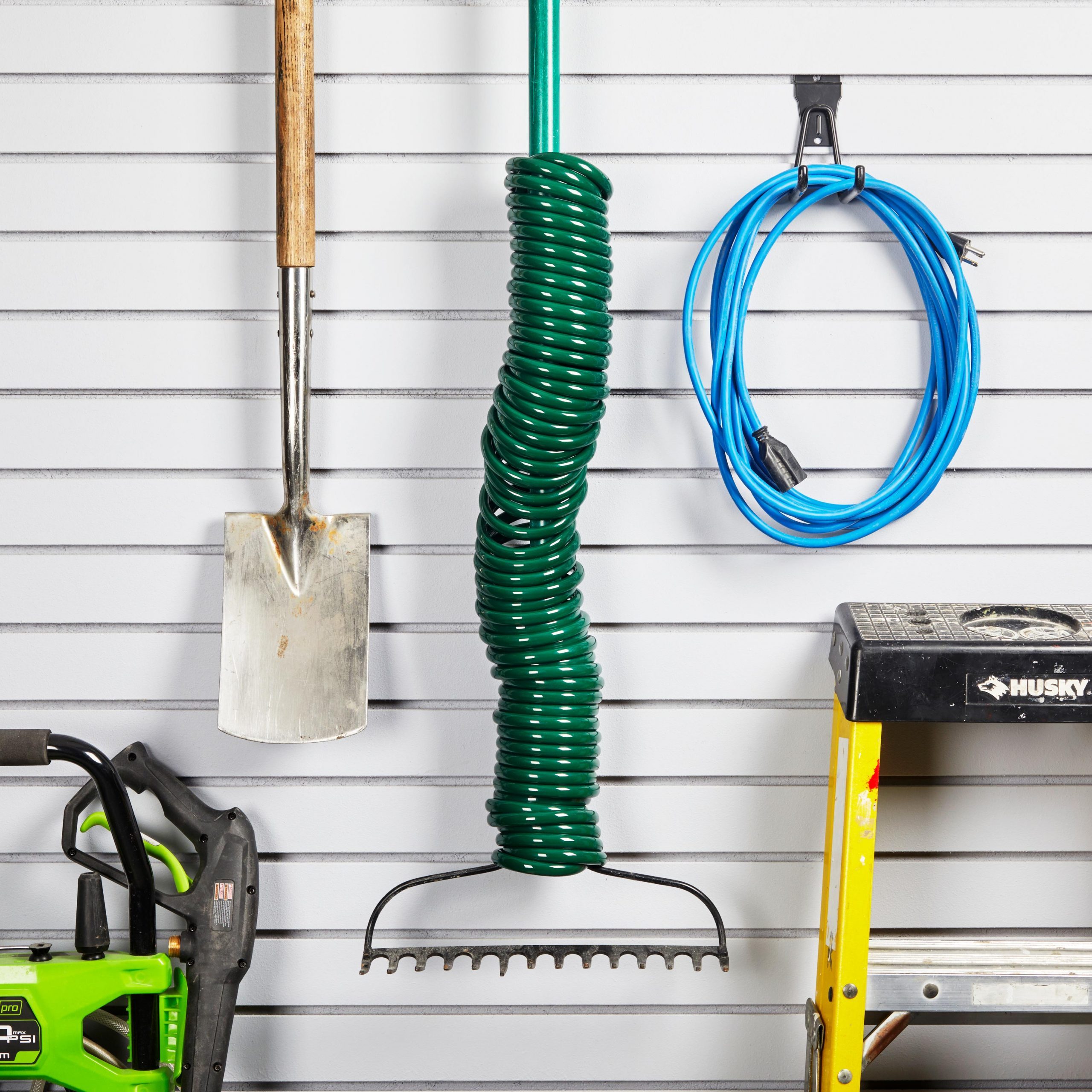 spiral hose on rake handle hanging on the side of a house